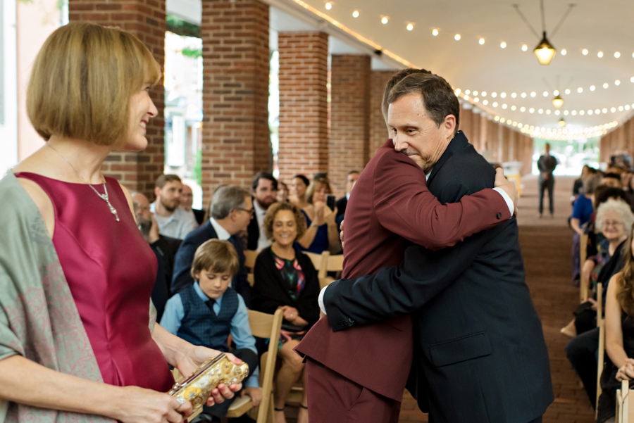 A groom hugging his father at the end of the isle before he sees his bride.